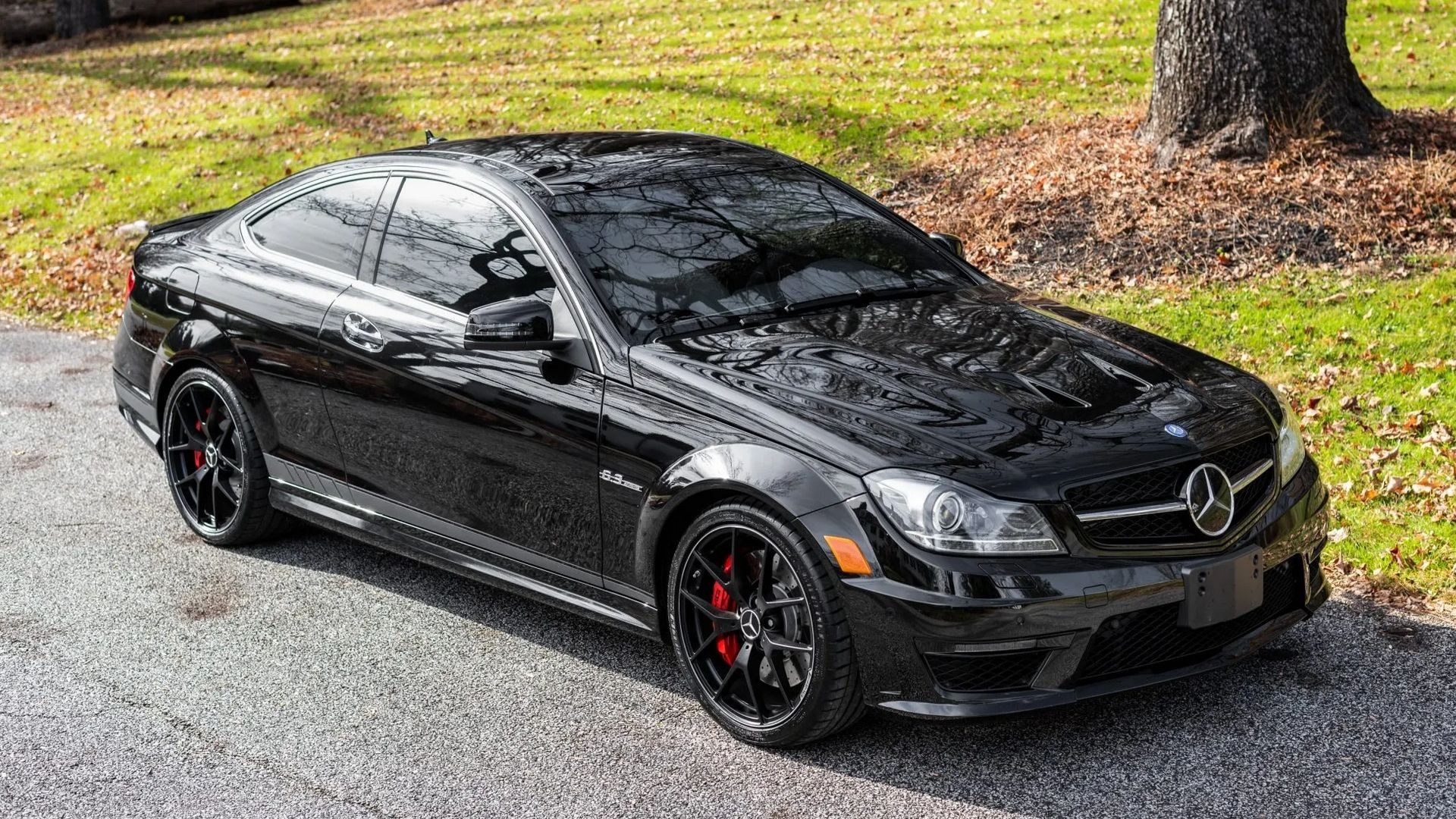 Black 2014 Mercedes-Benz C63 AMG on a paved surface, emphasizing its powerful and classic design.