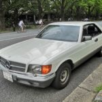 Front view of a silver Mercedes-Benz 500 SEC parked on a street, showcasing its iconic grille and headlights