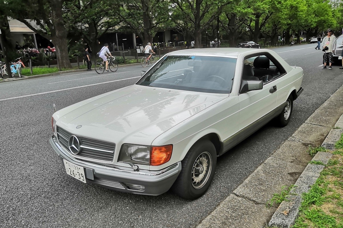 Front view of a silver Mercedes-Benz 500 SEC parked on a street, showcasing its iconic grille and headlights