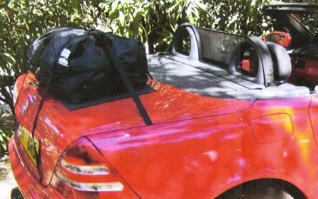 red Mercedes slk r170 next to a bush in shine under shade with a boot-bag trunk luggage rack fitted