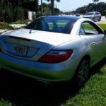 Side view of a silver 2015 Mercedes-Benz SLK 250 Roadster parked outdoors, showcasing its sleek design and convertible top