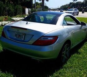 Side view of a silver 2015 Mercedes-Benz SLK 250 Roadster parked outdoors, showcasing its sleek design and convertible top