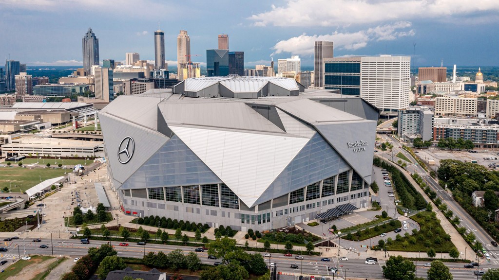 A stunning interior view of Mercedes-Benz Stadium showcasing the seating arrangement, the field, and the massive halo video board, highlighting the stadium's impressive scale and design.