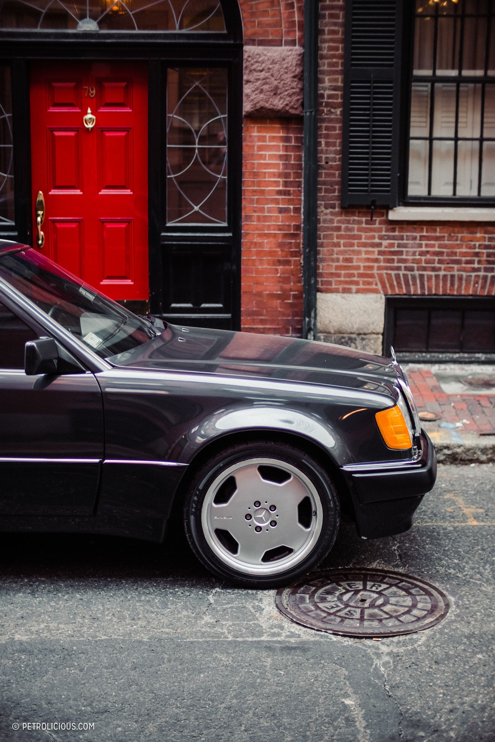 Front three quarter view of a black Mercedes-Benz 500E showing its wider stance and flared fenders.